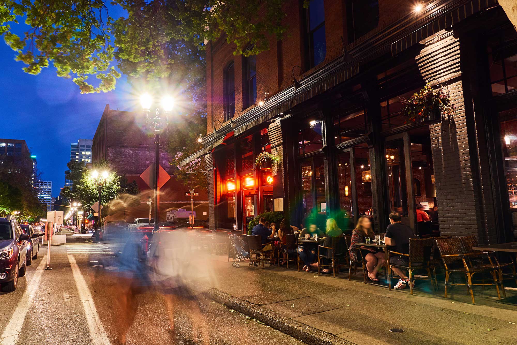 sidewalk view of people enjoying restaurants and the night life